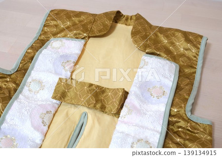一張特寫照片,展示了一件漂亮的兒童和服外套,上面有金色的七寶紋樣,非常適合慶祝活動。 一張特寫照片,展示了一件漂亮的兒童和服外套,上面有金色的七寶紋樣,非常適合慶祝活動。 139134915
