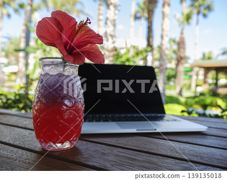 a red alcoholic cocktail and laptop on the table a red alcoholic cocktail and laptop on the table 139135018