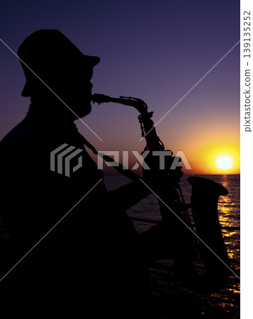 a musician playing the saxophone at sunset 139135252