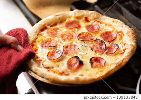 Bake a salami pepperoni pizza in the kitchen oven. 139135848