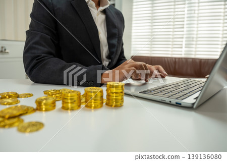Businessman calculating rising costs with gold coins, inflation and financial growth concept. 139136080