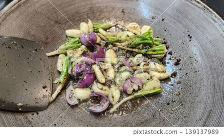 Sauteing Garlic, Shallots, and Cilantro Roots with Black Pepper in a Metal Wok 139137989