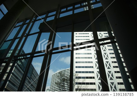 The view of the blue sky reflected in the windows of the buildings, seen through a large window. The view of the blue sky reflected in the windows of the buildings, seen through a large window. 139138785
