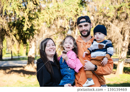 Family with mother father daughter and baby son standing together in park and smiling at camera. Concept of family relationship and parenting 139139469