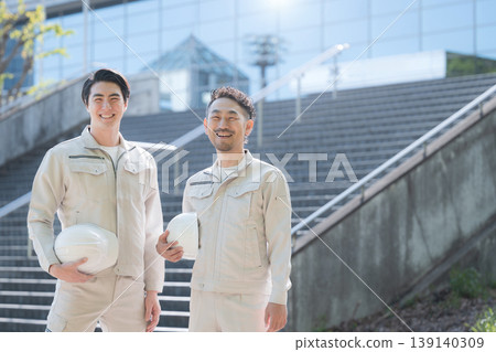 A portrait of a young worker holding a helmet, depicting a construction site and growth, with a building in the background representing the future and hope. A portrait of a young worker holding a helmet, depicting a construction site and growth, with a building in the background representing the future and hope. 139140309