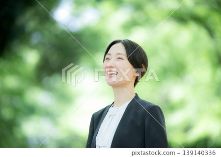 A full-body portrait of a female saleswoman walking through a park in the fresh greenery, a close-up of her upper body, looking up with hope and aspirations for the future. A full-body portrait of a female saleswoman walking through a park in the fresh greenery, a close-up of her upper body, looking up with hope and aspirations for the future. 139140336