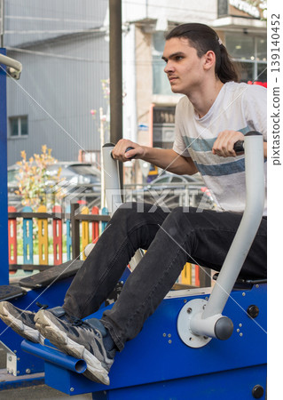A man works out on gym equipment in an outdoor park. A man works out on gym equipment in an outdoor park. 139140452