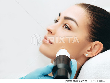 Rejuvenation of the face skin with the help of acoustic waves, closeup face of a beautiful woman Rejuvenation of the face skin with the help of acoustic waves, closeup face of a beautiful woman 139140629