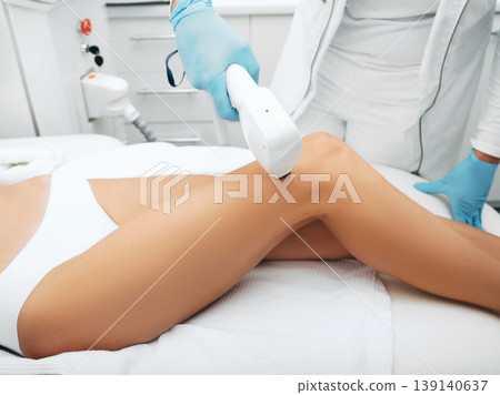 Laser hair removal on beautiful female legs. Laser cosmetologist doing legs smooth and hair free. Laser hair removal on beautiful female legs. Laser cosmetologist doing legs smooth and hair free. 139140637