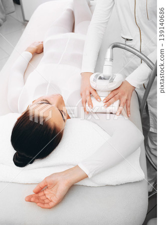 woman lying comfortably in a massage table during the LPG massage procedure. Beautician removes cululitis on a woman hand 139140686