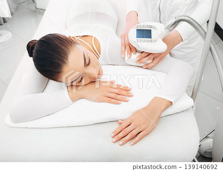Beautician doing LPG massage on the hand of a beautiful woman. Removing sagging skin on the arm and removing cilulitis 139140692
