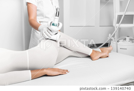 beautician doing lpg massage against cellulite on female leg 139140740