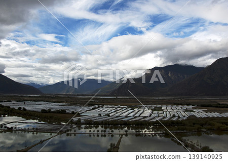 雲霧繚繞的山巒和森林,點綴著溫室和草地。 雲霧繚繞的山巒和森林,點綴著溫室和草地。 139140925