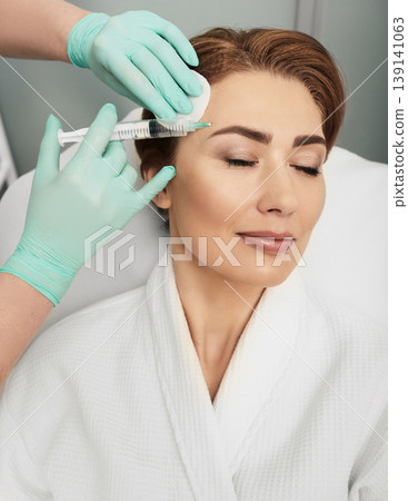 Beautiful woman during facial mesotherapy. Beautician doing anti-aging injection for tighten skin 139141063