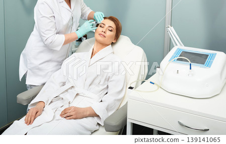 Mesotherapy procedure. Woman with closed eyes receives beauty injections for tightening and refreshing skin at medical clinic Mesotherapy procedure. Woman with closed eyes receives beauty injections for tightening and refreshing skin at medical clinic 139141065