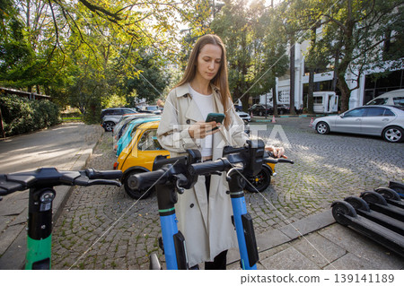 Young woman using mobile app to rent electric scooter in city Young woman using mobile app to rent electric scooter in city 139141189