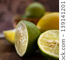 Green and yellow halves of fresh and juicy lemons. Close-up photo on dark background 139141201