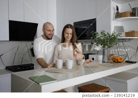 Smiling couple drinking tea at home kitchen Smiling couple drinking tea at home kitchen 139141219