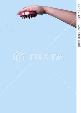 Hair brush for stimulating hair growth on blue background. Microcirculation, help to distribute natural oils more evenly across the scalp. Vertical Hair brush for stimulating hair growth on blue background. Microcirculation, help to distribute natural oils more evenly across the scalp. Vertical 139141235