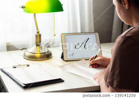 Person seated at desk deeply focused on writing in notebook. Physical engagement of motor skills Handwriting as brain training. Prevention of age related cognitive decline. Senior or adult practicing Person seated at desk deeply focused on writing in notebook. Physical engagement of motor skills Handwriting as brain training. Prevention of age related cognitive decline. Senior or adult practicing 139141250