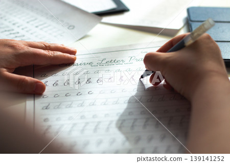 Quiet scene of woman writing with pen. Training accurate handwriting. Therapeutic habit to reduce anxiety and increase clarity. Calmness and digital detox Quiet scene of woman writing with pen. Training accurate handwriting. Therapeutic habit to reduce anxiety and increase clarity. Calmness and digital detox 139141252