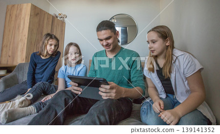 Group of children watching a video together on a tablet in a living room during the afternoon Group of children watching a video together on a tablet in a living room during the afternoon 139141352