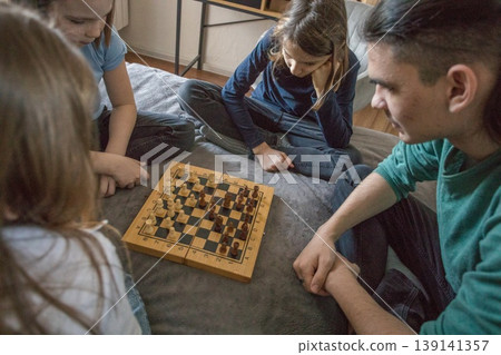 Group plays chess in a cozy room on a soft surface during a late afternoon gathering Group plays chess in a cozy room on a soft surface during a late afternoon gathering 139141357