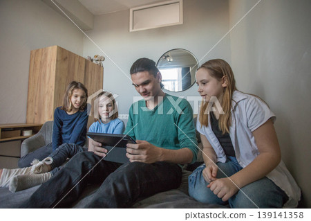 Group of children watching a video together on a tablet in a living room during the afternoon Group of children watching a video together on a tablet in a living room during the afternoon 139141358