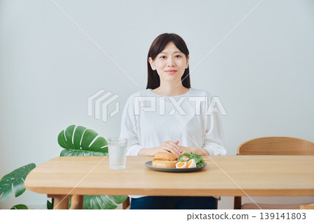 一位女士正在享用健康的早餐;這是均衡飲食的象徵。 一位女士正在享用健康的早餐;這是均衡飲食的象徵。 139141803