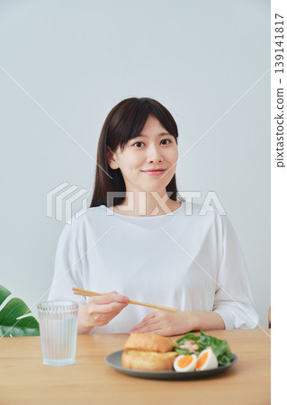 一位女士正在享用健康的早餐;這是均衡飲食的象徵。 一位女士正在享用健康的早餐;這是均衡飲食的象徵。 139141817