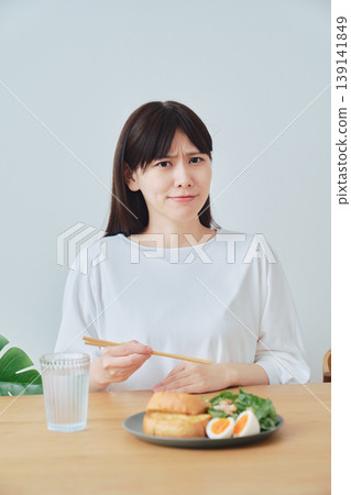 一位女士在早餐時感到不適；食慾不振的畫面。 139141849