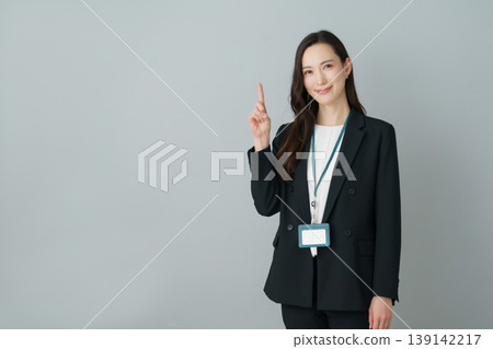 A young Japanese woman in a suit strikes the first pose against a gray background. A young Japanese woman in a suit strikes the first pose against a gray background. 139142217