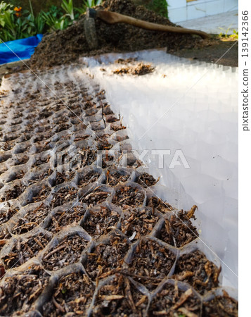 Close up view of a transparent plastic honeycomb grid partially filled with dark brown soil in a gardening setting Close up view of a transparent plastic honeycomb grid partially filled with dark brown soil in a gardening setting 139142366