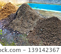 High angle view of three different heaps of organic gardening materials including soil, compost, and rice husks on a wet concrete floor. 139142367