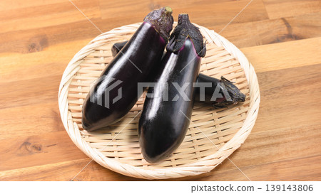 Close-up of fresh eggplants on a basket; vegetable ingredients on a wooden table. Close-up of fresh eggplants on a basket; vegetable ingredients on a wooden table. 139143806