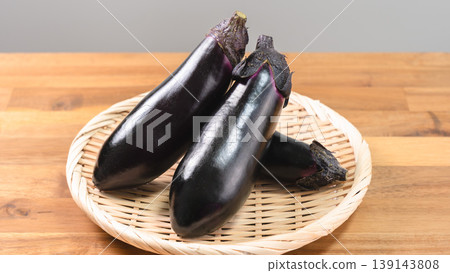 Close-up of fresh eggplants on a basket; vegetable ingredients on a wooden table. Close-up of fresh eggplants on a basket; vegetable ingredients on a wooden table. 139143808
