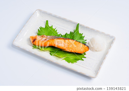 鹽烤鮭魚配上磨碎的白蘿蔔：一道經典的日式烤魚料理，盛放在長長的白色盤子裡。 139143821