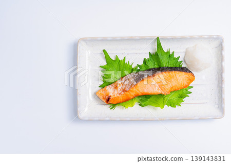 鹽烤鮭魚配上磨碎的白蘿蔔：一道經典的日式烤魚料理，盛放在長長的白色盤子裡。 139143831
