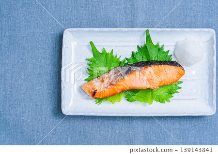 Salt-grilled salmon with grated daikon radish: A classic Japanese dish of grilled fish served on a long white plate. 139143841
