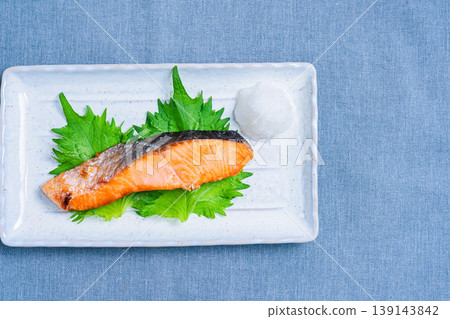 Salt-grilled salmon with grated daikon radish: A classic Japanese dish of grilled fish served on a long white plate. 139143842