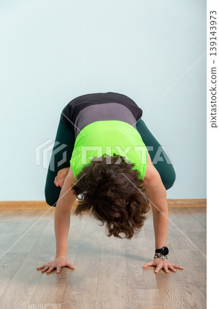 Woman practicing yoga in a forward bend on a wooden floor Woman practicing yoga in a forward bend on a wooden floor 139143973