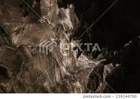 Dimly lit limestone cave ceiling showing dramatic stalactites Dimly lit limestone cave ceiling showing dramatic stalactites 139144700