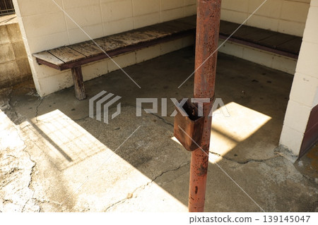 The rusty ashtray and well-worn bench tell the story of the waiting room. The rusty ashtray and well-worn bench tell the story of the waiting room. 139145047
