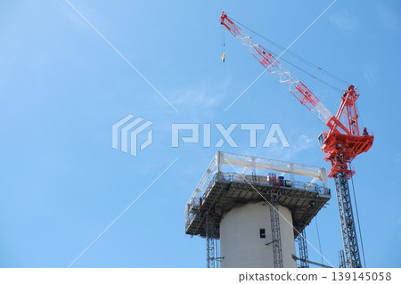 Construction cranes and tower tops stretch towards the clear blue sky. Construction cranes and tower tops stretch towards the clear blue sky. 139145058