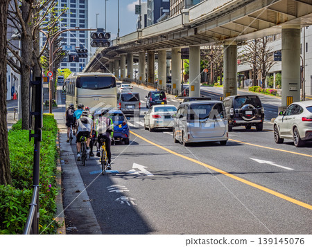 一條安全的城市道路,自行車和汽車都遵守車道劃分;這是交通規則遵守的典範。 一條安全的城市道路,自行車和汽車都遵守車道劃分;這是交通規則遵守的典範。 139145076