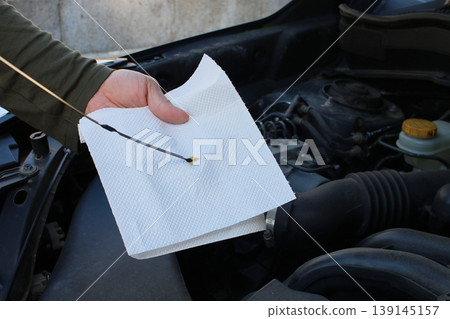 A man checking the engine oil. 139145157
