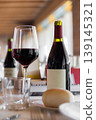 Glass of Red Wine and Bottle on Restaurant Table with Bread and Glassware 139145321