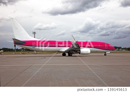 Passenger red white plane at the airport. Place for text. Clouds sky. Runway. Travel. Taxiing. Takeoff and landing. Arrival and departure. Passenger red white plane at the airport. Place for text. Clouds sky. Runway. Travel. Taxiing. Takeoff and landing. Arrival and departure. 139145613