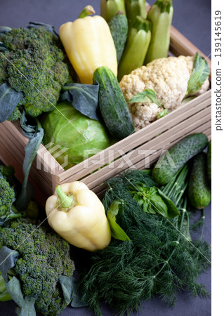 Vegetable basket. Fresh vegetables on the table black background. Set of food delivery box. Broccoli, cabbage, eggplant, white cabbage, cucumber, dill, cauliflower. Stilllife top view. Vegetable basket. Fresh vegetables on the table black background. Set of food delivery box. Broccoli, cabbage, eggplant, white cabbage, cucumber, dill, cauliflower. Stilllife top view. 139145619
