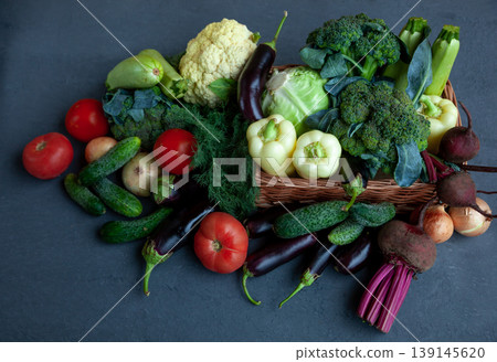 Vegetable basket. Fresh vegetables on the table black background. Set of food delivery box. Broccoli, cabbage, eggplant, white cabbage, cucumber, dill, cauliflower. Stilllife top view. Vegetable basket. Fresh vegetables on the table black background. Set of food delivery box. Broccoli, cabbage, eggplant, white cabbage, cucumber, dill, cauliflower. Stilllife top view. 139145620